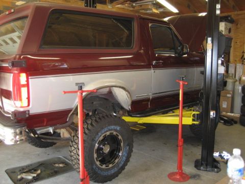 1996 Ford Bronco - 1996 Ford Bronco is being serviced on a car lift in a workshop.