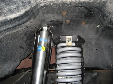 1996 Ford Bronco - Close-up view of suspension components, including a shock absorber and coil spring, within a vehicle's wheel well.