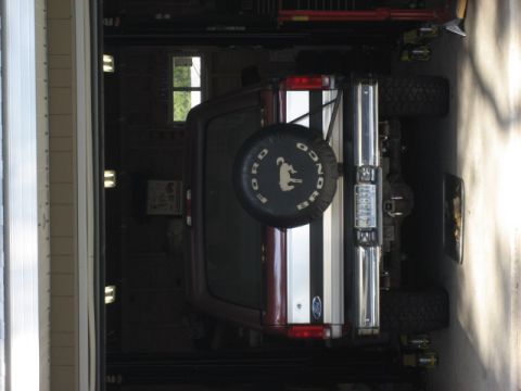 1996 Ford Bronco - This Ford Bronco is parked inside a garage, showing its rear end and spare tire cover.