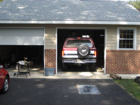 1996 Ford Bronco - The rear of a red 1996 Ford Bronco is parked in a garage, a spare tire mounted on the tailgate.