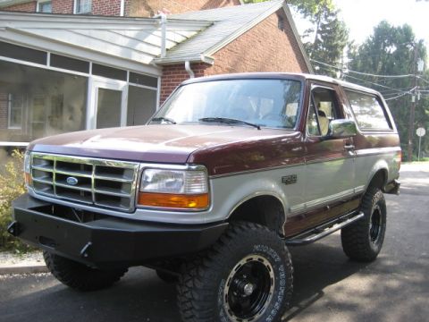 1996 Ford Bronco - This 1996 Ford Bronco features a two-tone paint scheme, an aftermarket front bumper, and lifted suspension with large off-road tires.