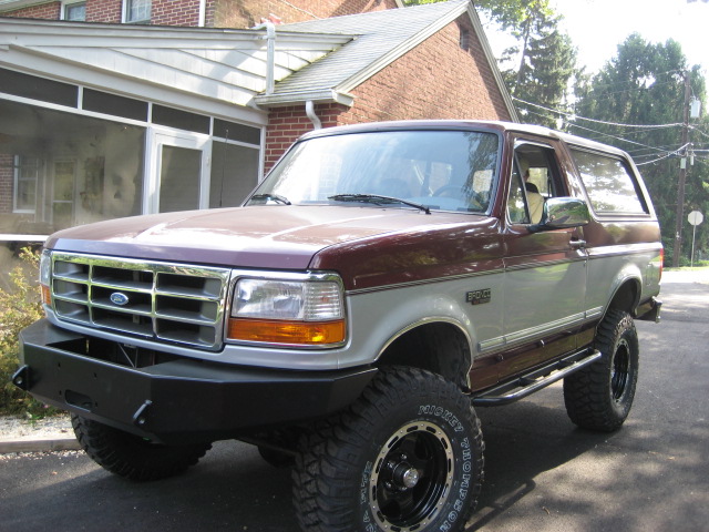 Maroon and silver 1996 Ford Bronco with aftermarket bumper and large tires