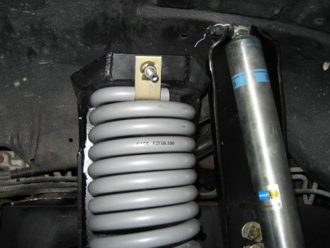 1996 Ford Bronco - Close-up view of vehicle suspension components, including a coil spring and shock absorber.