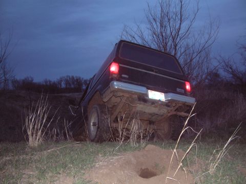 1984 Ford Bronco II - A black 1984 Ford Bronco II navigates rough terrain in the twilight.
