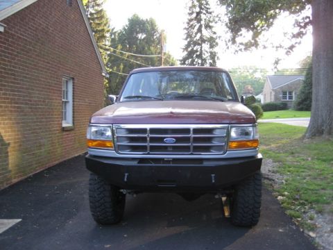 1996 Ford Bronco - A maroon Ford Bronco is parked in a driveway next to a brick house.