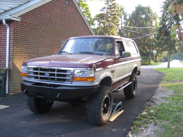 Maroon and silver 1996 Ford Bronco with aftermarket bumper and large tires parked on a driveway