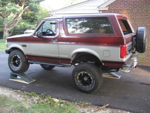 1996 Ford Bronco - This two-tone Ford Bronco is parked on ramps in a driveway, with a spare tire mounted on the rear.