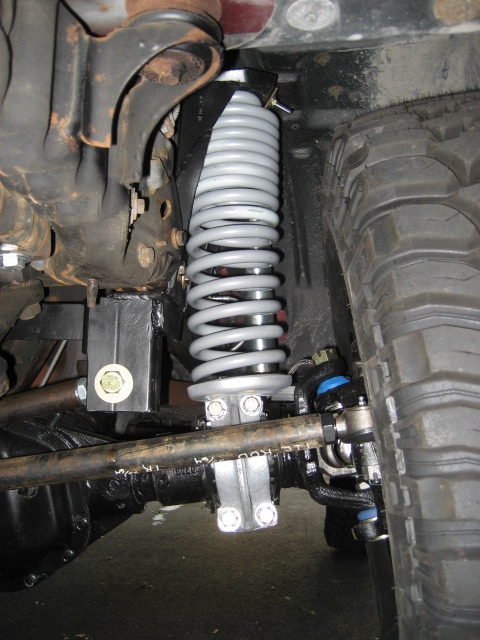 1996 Ford Bronco - This image shows the suspension components of a vehicle, including a coilover shock absorber and part of the tire.