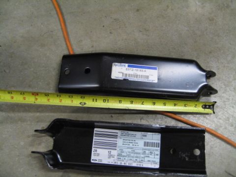 1996 Ford Bronco - Two metal automotive parts are shown with a measuring tape to indicate their size.