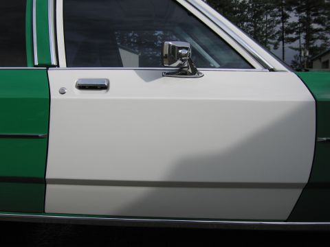 1991 Ford LTD Crown Victoria - Close-up of the white front door, chrome side mirror and door handle on a two-tone green and white sedan.