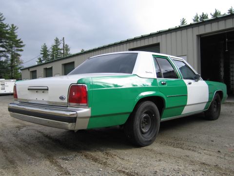 1991 Ford LTD Crown Victoria - green and white full-size Ford sedan shown from the rear three-quarter, with wraparound taillights and a chrome bumper.