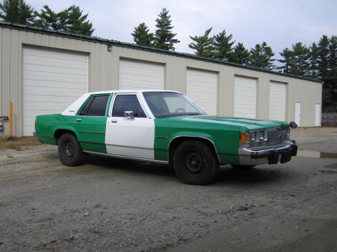 1991 Ford LTD Crown Victoria - Front passenger-side three-quarter view of a green and white full-size Ford sedan parked on gravel by storage units.