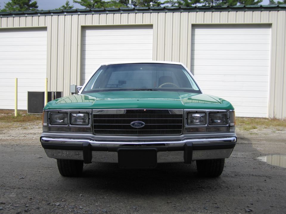 Front of green Ford sedan with Ford grille emblem and dual headlights