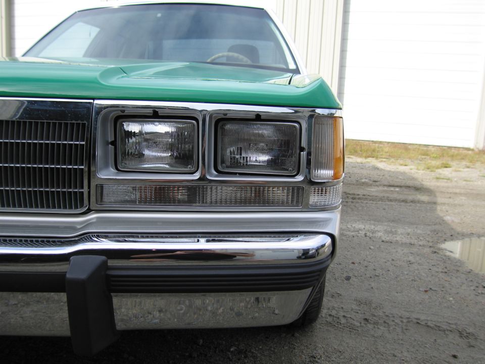 Close-up of green Ford front end, dual rectangular headlights and chrome bumper