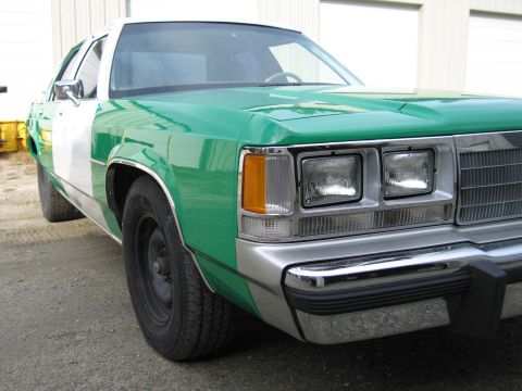 1991 Ford LTD Crown Victoria - Front three-quarter close-up of a green-and-white full-size Ford sedan focused on the headlights, grille and chrome bumper.