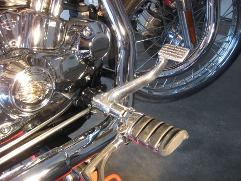 2004 Harley-Davidson Sportster Custom - Close-up of a motorcycle's engine and foot controls, showing chrome detailing and a spoked wheel.