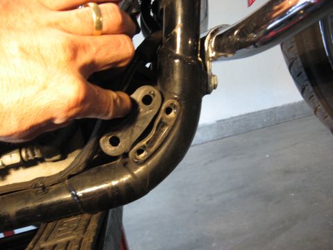 2004 Harley-Davidson Sportster Custom - Close-up of a motorcycle's frame with a hand indicating a mounting bracket. The Supermotors.net logo is visible.