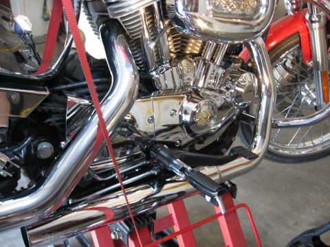 2004 Harley-Davidson Sportster Custom - Close-up of a motorcycle's engine and exhaust system, supported by a red stand.