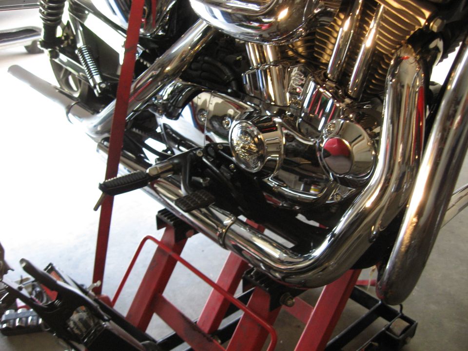 2004 Harley-Davidson Sportster Custom engine and exhaust pipes on a red lift