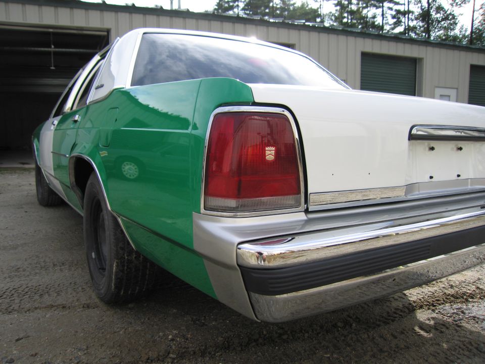 Rear quarter of green and white Ford sedan, taillight and chrome bumper