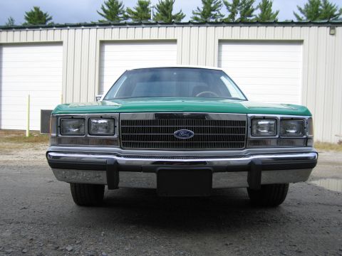 1991 Ford LTD Crown Victoria - Straight-on front view of a green-and-white full-size Ford sedan with Ford grille emblem and stacked dual rectangular headlights.