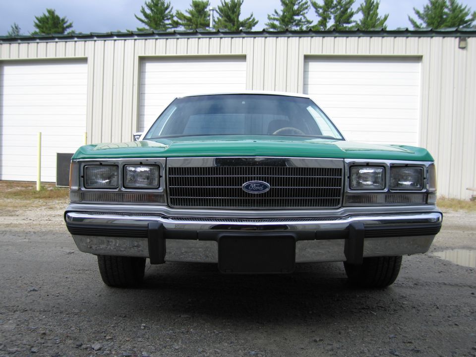 Front of green and white Ford sedan with Ford grille emblem, dual headlights