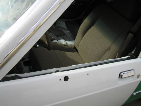 1991 Ford LTD Crown Victoria - View through an open front door of a white Ford sedan revealing tan cloth bucket-style front seats and door panel.