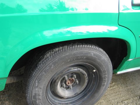 1991 Ford LTD Crown Victoria - Close-up of a green Ford front fender and steel wheel fitted with a Firestone tire.