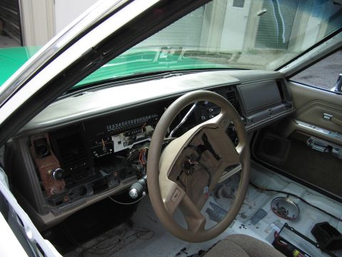 1991 Ford LTD Crown Victoria - tan dashboard and steering wheel of a sedan with the floor stripped to bare metal and wiring exposed during restoration.