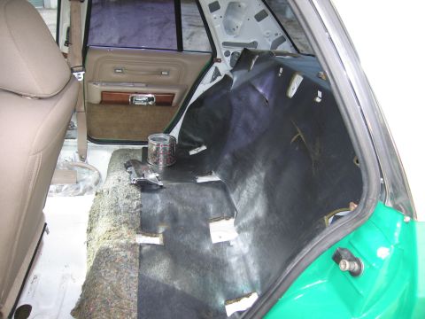 1991 Ford LTD Crown Victoria - rear interior of a sedan with the seat removed, showing bare floor, sound-deadening matting and a tan door panel.