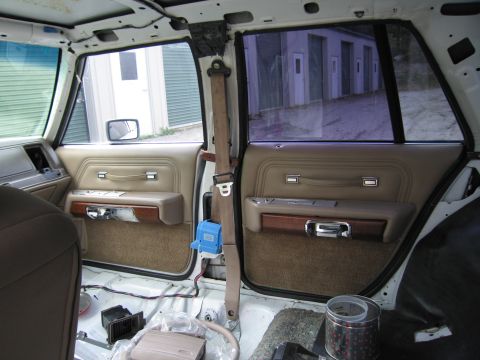 1991 Ford LTD Crown Victoria - Interior view of a stripped sedan showing two tan rear door panels with woodgrain trim and the bare painted floor.