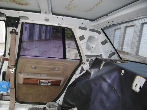 1991 Ford LTD Crown Victoria - exposed bare-metal roof structure of a sedan with the headliner removed, beside a tan rear door panel.