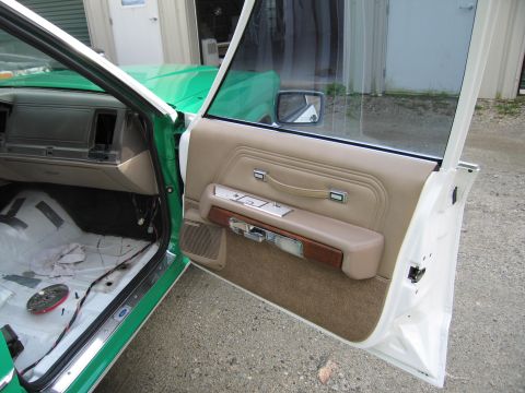 1991 Ford LTD Crown Victoria - open white front door of a sedan with a tan padded door panel, beside a stripped bare-metal interior floor.