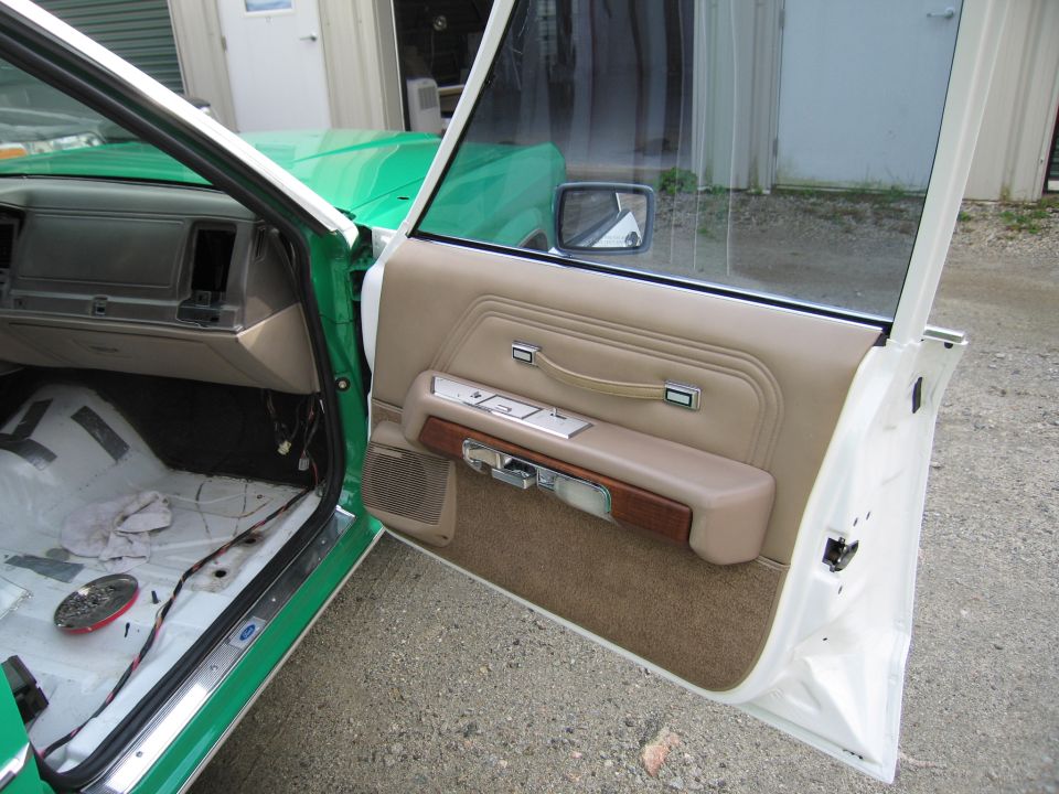 Open front door of sedan with tan door panel and stripped interior floor