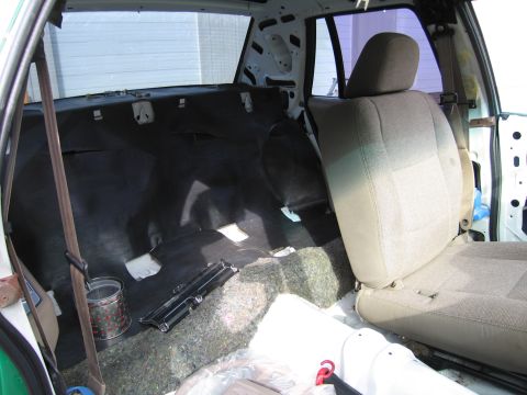1991 Ford LTD Crown Victoria - rear seat and trunk area of a sedan with carpet pulled back and tan cloth seats during interior restoration.