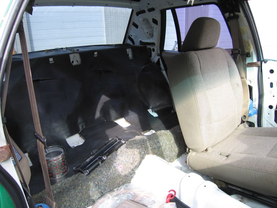 Rear cargo and seat area of sedan with carpet pulled up during restoration