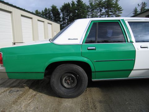 1991 Ford LTD Crown Victoria - rear quarter of a green-and-white Ford sedan showing the wheel, window and an LTD Crown Victoria fender badge.