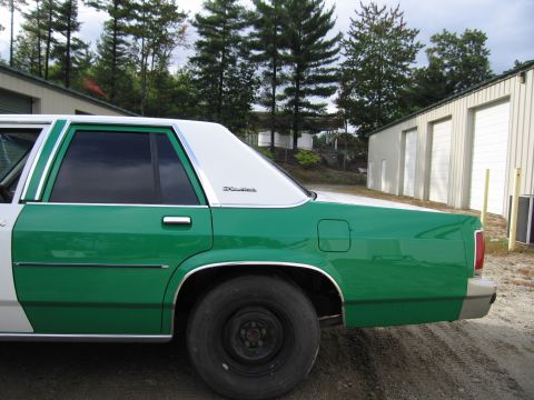 1991 Ford LTD Crown Victoria - rear side of a green-and-white sedan showing tinted windows and a Crown Victoria badge on the rear door.