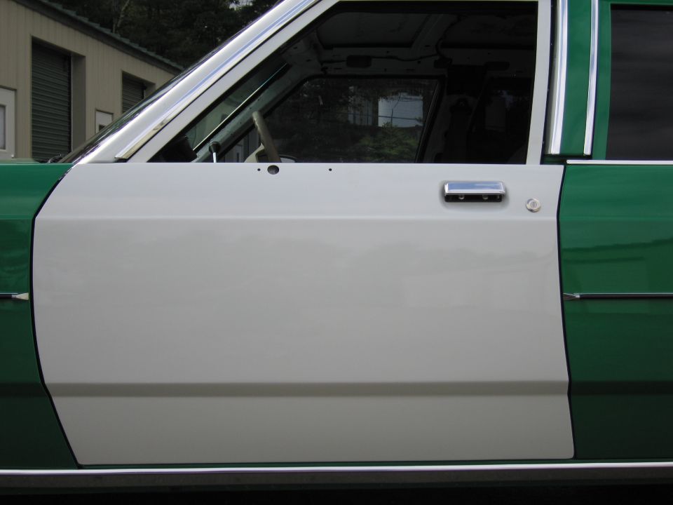 Close-up of white front door with chrome handle on green and white sedan