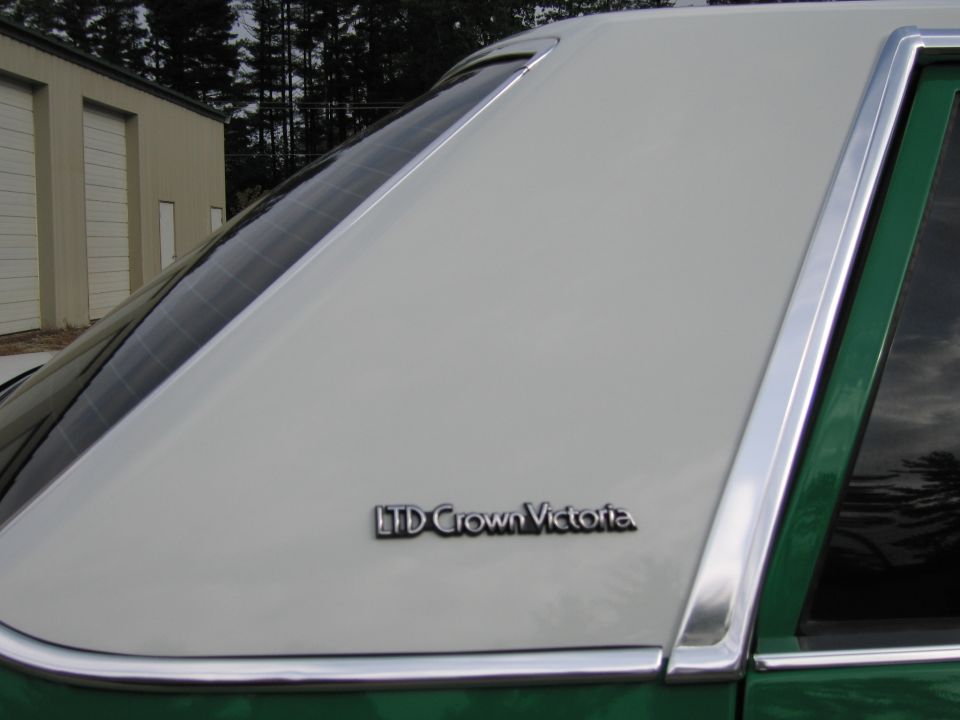 Green sedan rear C-pillar and quarter window with "LTD Crown Victoria" emblem outdoors