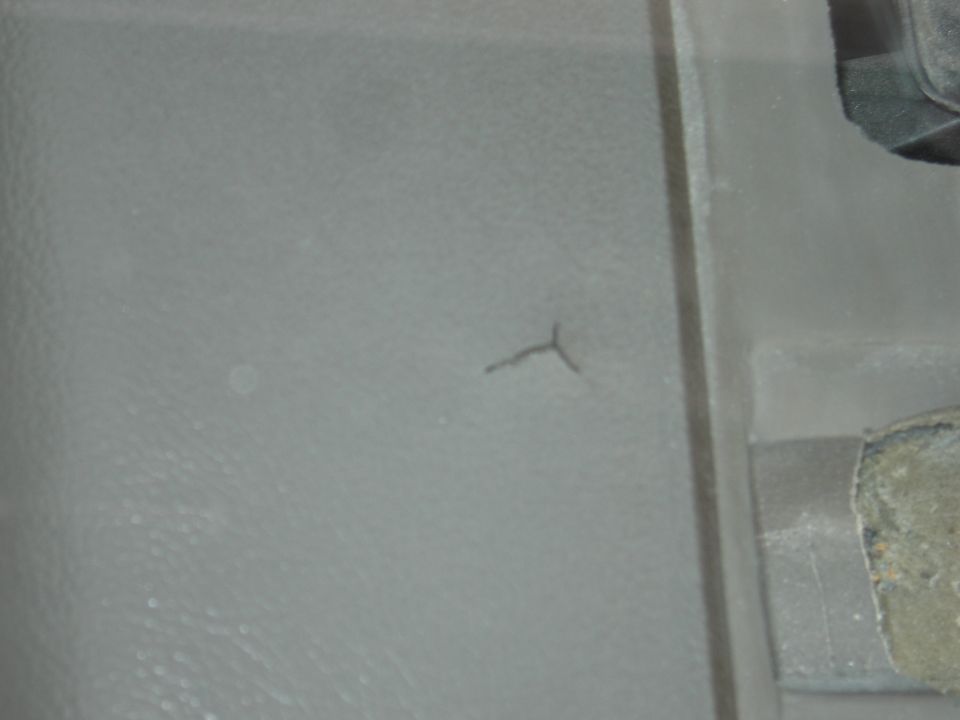 Close-up of gray textured plastic trim panel with a small crack and bolts
