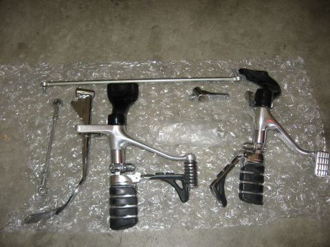 2004 Harley-Davidson Sportster Custom - Various motorcycle foot controls are displayed on a textured surface, with a website URL visible at the bottom right.