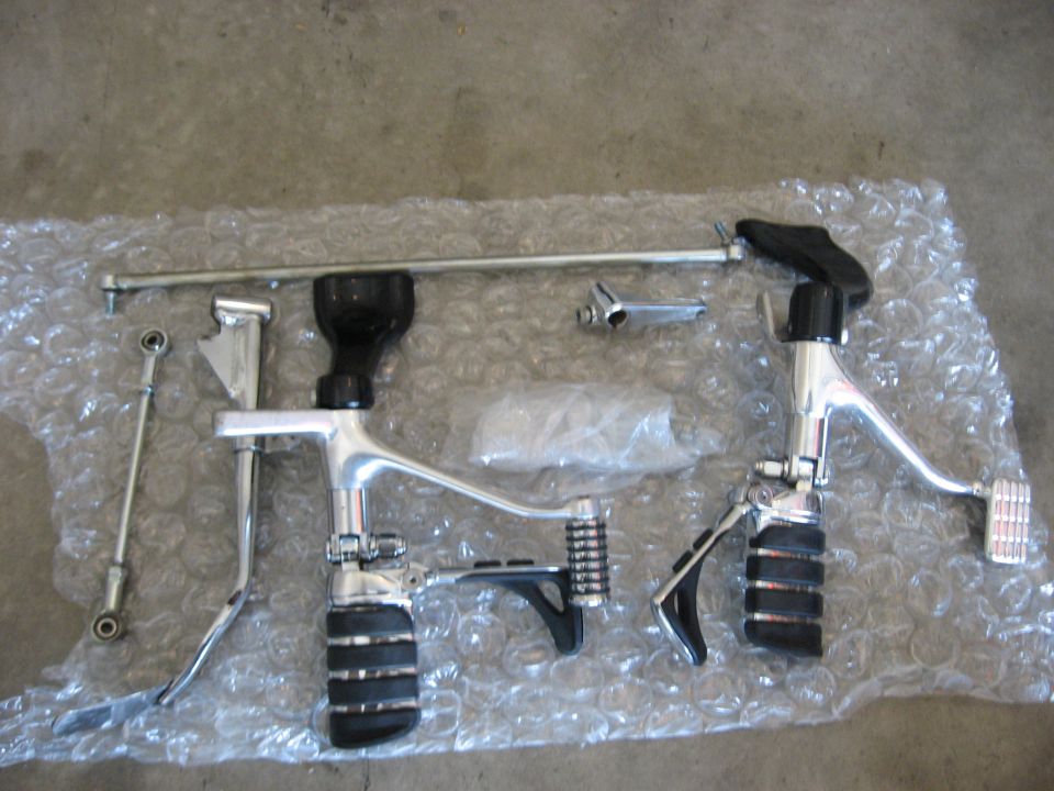 Chrome and black motorcycle foot controls laid out on bubble wrap