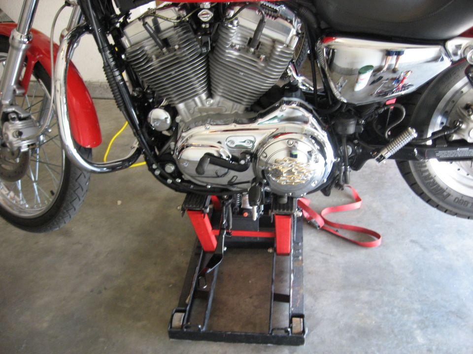 Harley-Davidson V-twin motorcycle on a red lift stand in a garage