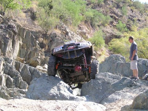 1986 Toyota Hilux - A heavily modified off-road truck navigates a rocky trail, demonstrating impressive articulation.