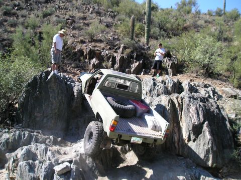 1986 Toyota Hilux - Pickup truck navigates a challenging rocky trail in a desert environment.