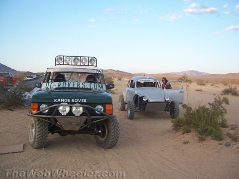 1990 Ford Bronco - green Range Rover off-road racer and a silver Baja Bug sit on the open desert at dusk.