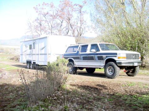 1994 Ford C-350 (Centurion Conversions) - This Ford F-350 Centurion Conversion SUV tows a travel trailer on a dirt road.