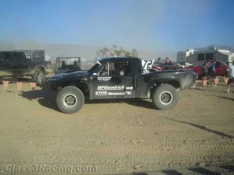 1990 Ford Bronco - black trophy-truck style off-road racer numbered 72 with BFGoodrich lettering sits on a dusty desert course.