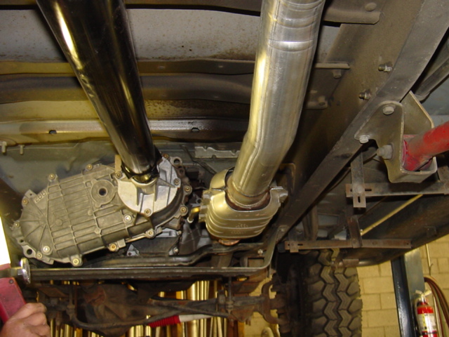Vehicle undercarriage showing transfer case, dual metal tubes, frame rail and tire